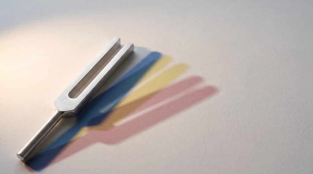 A single tuning fork casting several different colored shadows, representing one steady brand voice adapting its tone to different situations