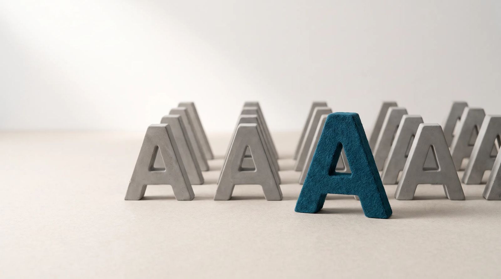 One distinct, colorful letter standing out among rows of identical grey letters, representing a brand finding its own voice